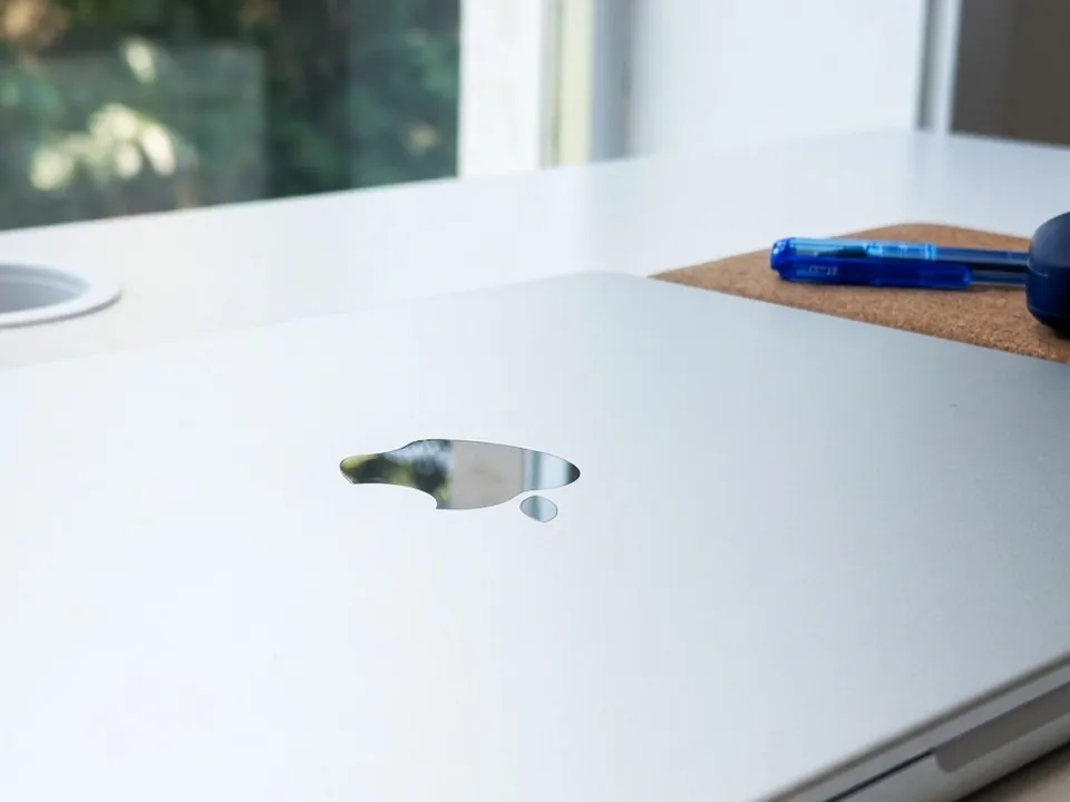 Closed silver laptop on a white desk beside a sunny window